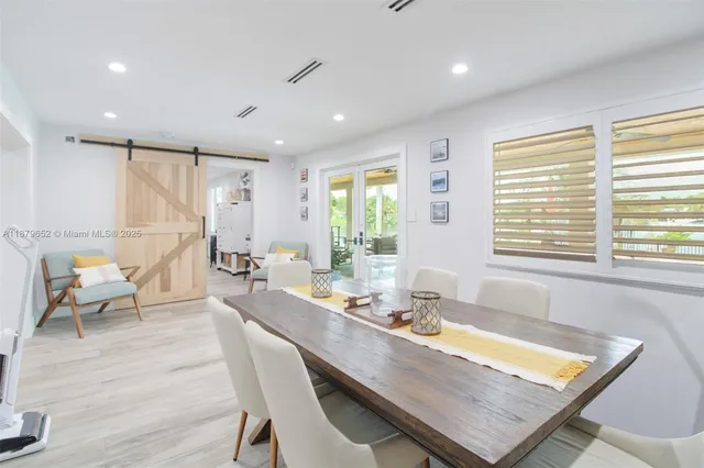 a dining room with wooden floor and large windows