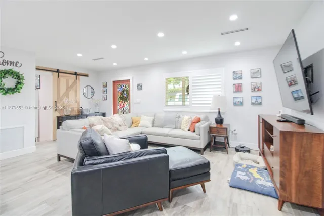 a living room with furniture a flat screen tv and a window