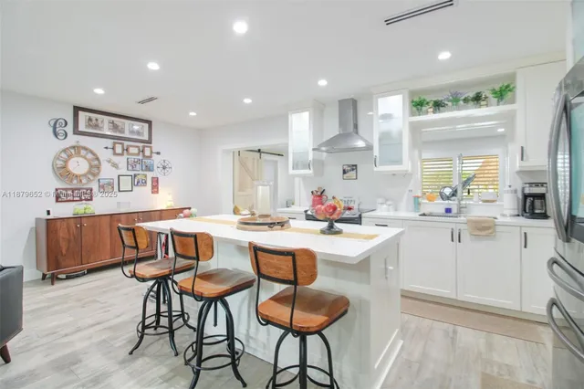 a kitchen with stainless steel appliances kitchen island granite countertop a dining table chairs and white cabinets