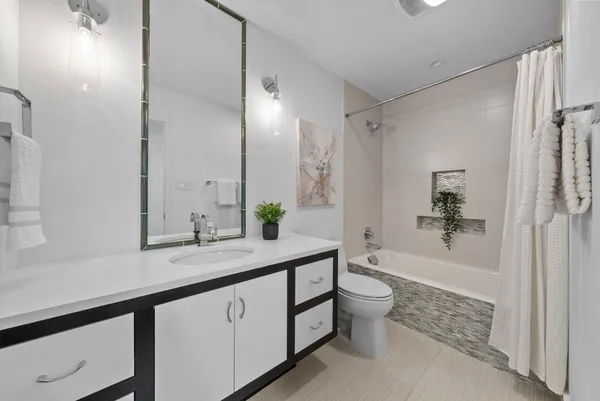 a spacious bathroom with a granite countertop sink a toilet a mirror and a shower