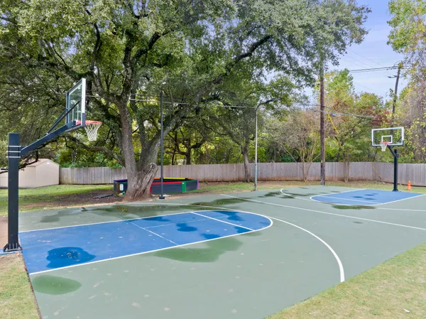 a view of a tennis ground with large trees