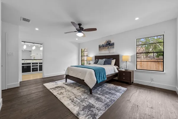 a bedroom with a large bed a chandelier and windows