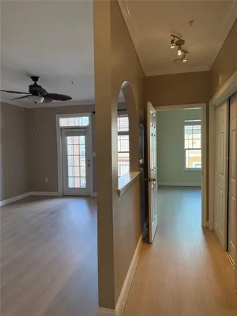 an empty room with a window and chandelier fan