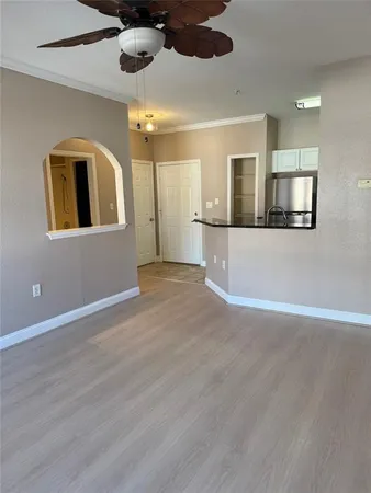 a view of a refrigerator in kitchen and an empty room in wooden floor