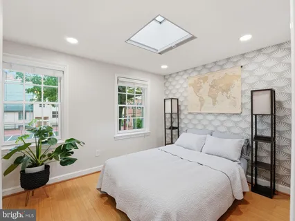 a bedroom with a bed potted plant on dresser and a window