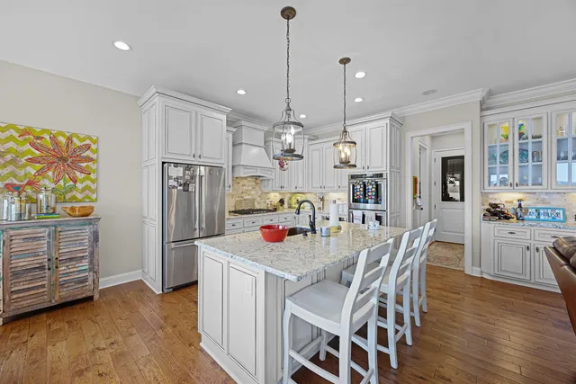 a kitchen with stainless steel appliances granite countertop a dining table chairs refrigerator and microwave