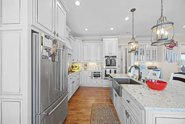 a kitchen with stainless steel appliances granite countertop a refrigerator a sink dishwasher a oven and a dining table with wooden floor