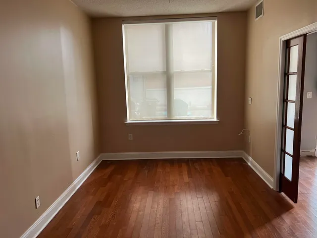 an empty room with wooden floor and windows