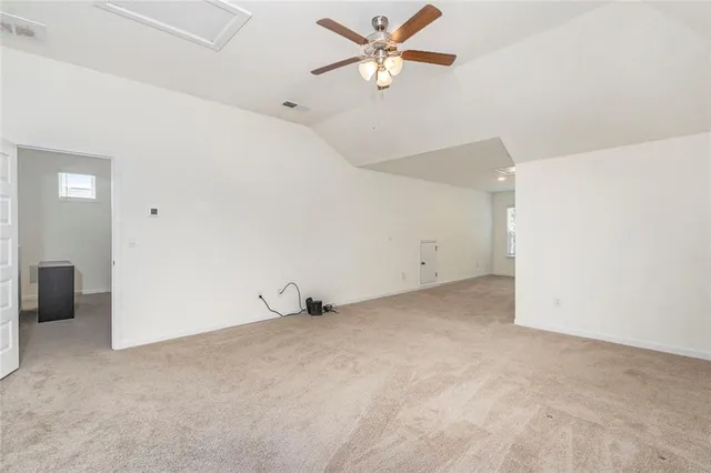 an empty room with a ceiling fan and carpet