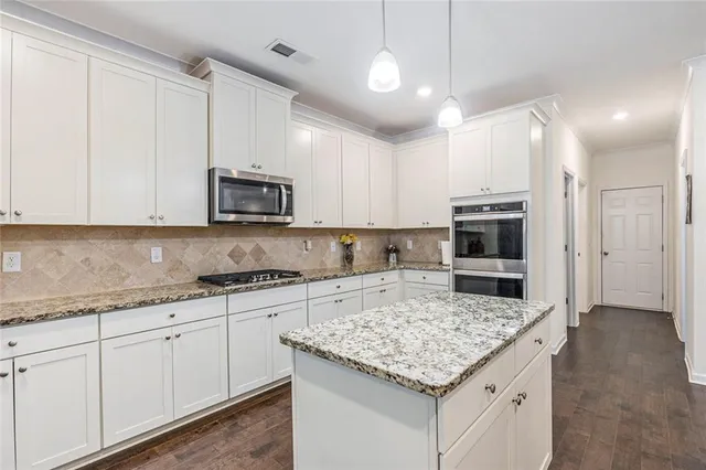 a kitchen with stainless steel appliances granite countertop a stove top oven a sink and a microwave