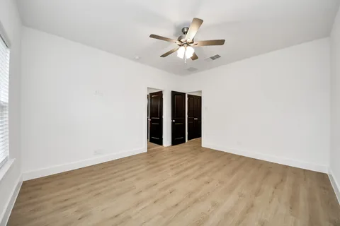 a view of an empty room with chandelier fan and wooden floor