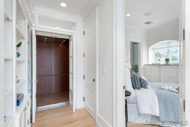 a spacious bedroom with a bed a chandelier and large window