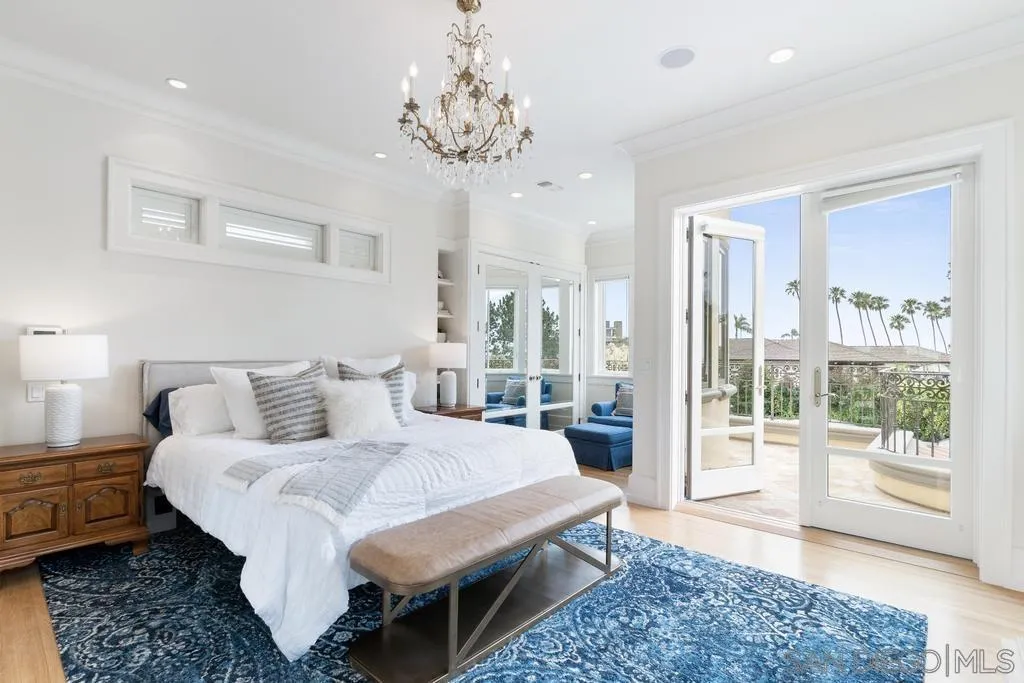 7971 Prospect Place La Jolla, CA 92037 - Photo 19 of 36 a spacious bedroom with a bed a chandelier and large window
