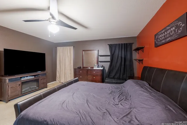 a bedroom with a bed and a flat tv screen on wall