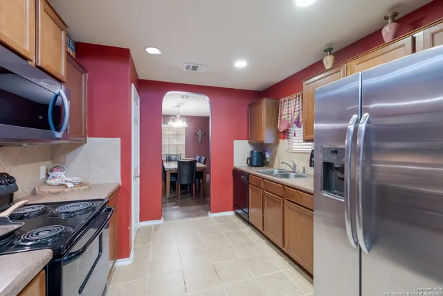 a kitchen with stainless steel appliances granite countertop a stove top oven a sink dishwasher a refrigerator and a dining table with wooden floor