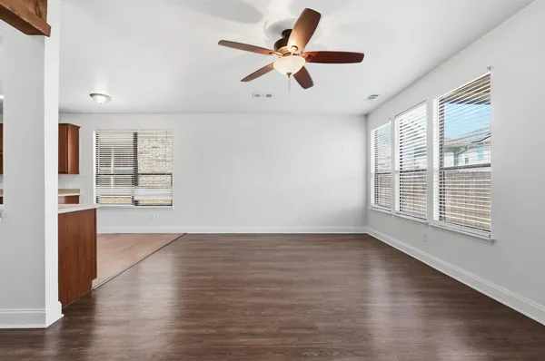 a view of an empty room with a window and wooden floor