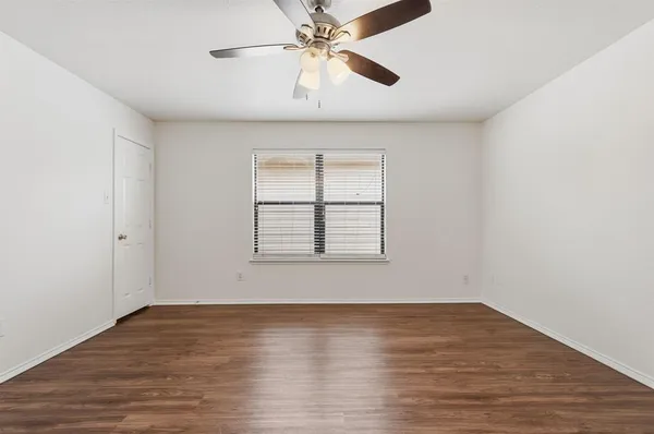 an empty room with wooden floor chandelier fan and windows