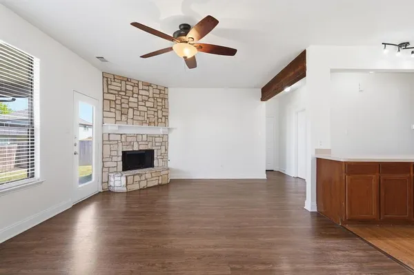 an empty room with wooden floor fireplace and windows