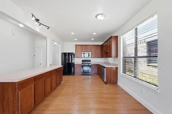 a large kitchen with stainless steel appliances kitchen island granite countertop a large counter top a stove a sink cabinets and a wooden floor