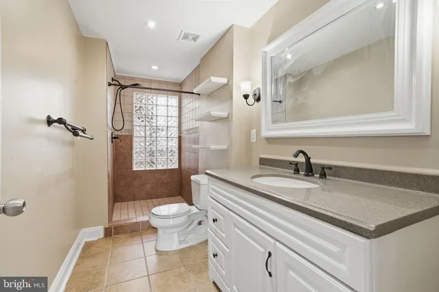 a bathroom with a granite countertop sink mirror vanity and toilet