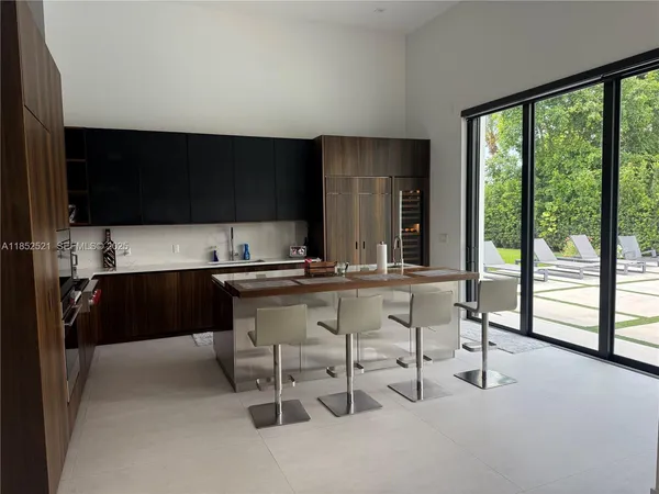 a kitchen with stainless steel appliances a stove a sink a refrigerator and chairs