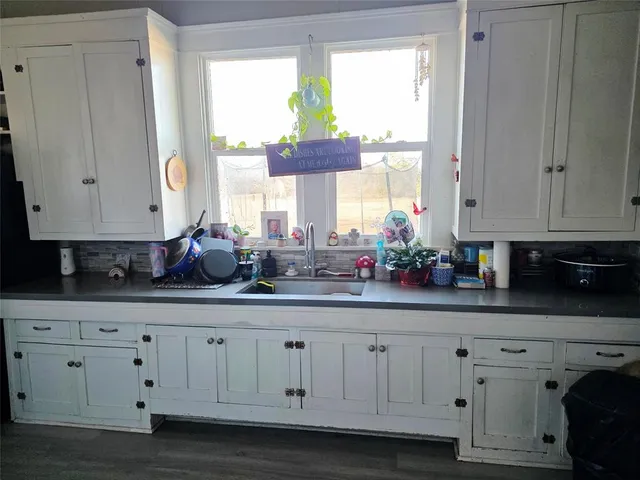 a kitchen with white cabinets and a window