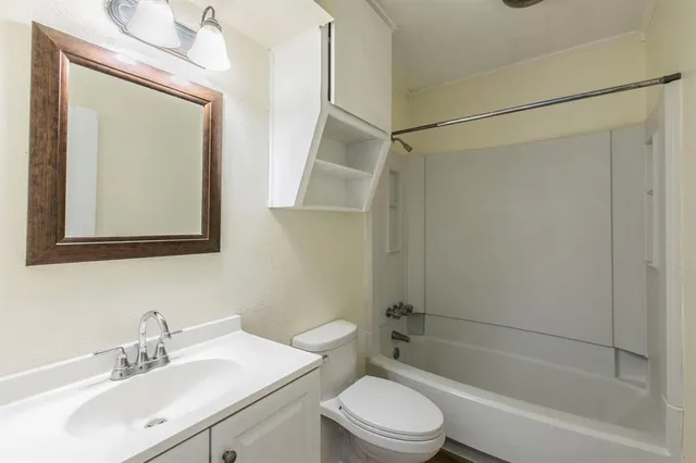a bathroom with a bathtub shower sink vanity mirror and toilet