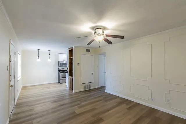 a view of a room with wooden floor and chandelier fan