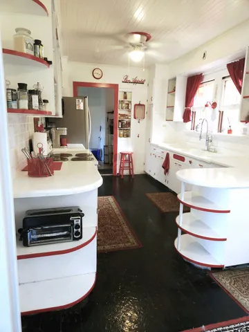 a view of living room kitchen with stainless steel appliances wooden floor and stove
