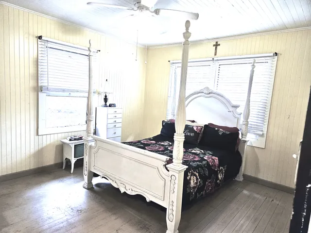 a bedroom with a bed large window with table and chair