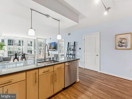 a kitchen with stainless steel appliances granite countertop a sink a counter space and wooden floor