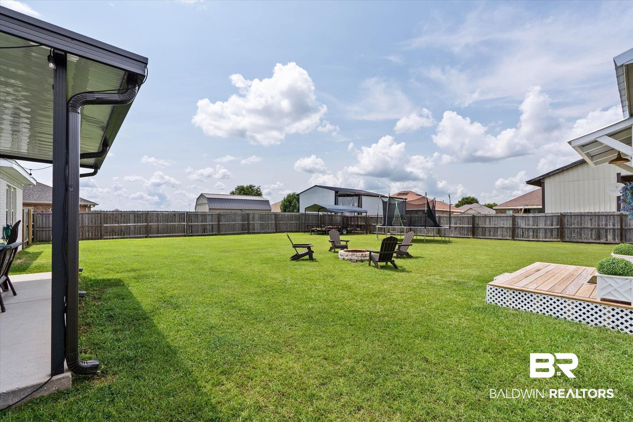 9074 Moses Way Theodore, AL 36582 - Photo 51 of 52 Expansive backyard featuring a large green lawn, full privacy fencing, and a dedicated patio space with a modern awning