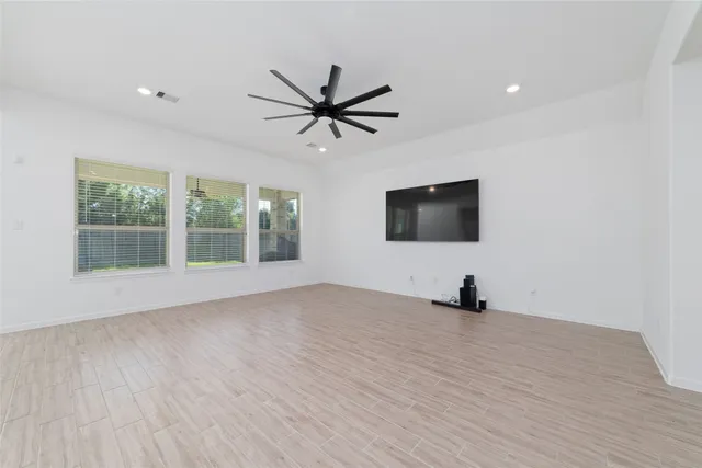 a view of a livingroom with a flat screen tv ceiling fan and hardwood floor