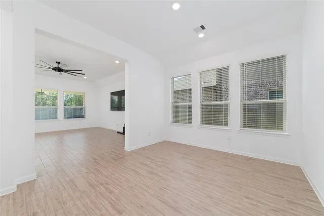 a view of an empty room with a window and wooden floor