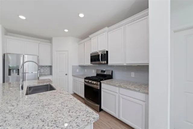 a kitchen with granite countertop white cabinets and stainless steel appliances