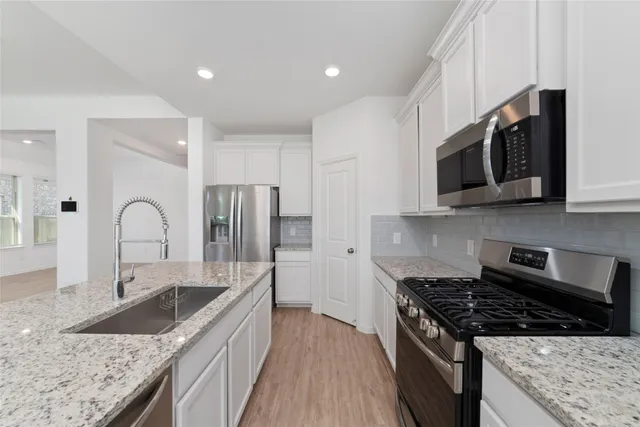 a kitchen with stainless steel appliances granite countertop a sink a stove and a refrigerator