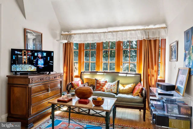 a living room with furniture a flat screen tv and a floor to ceiling window