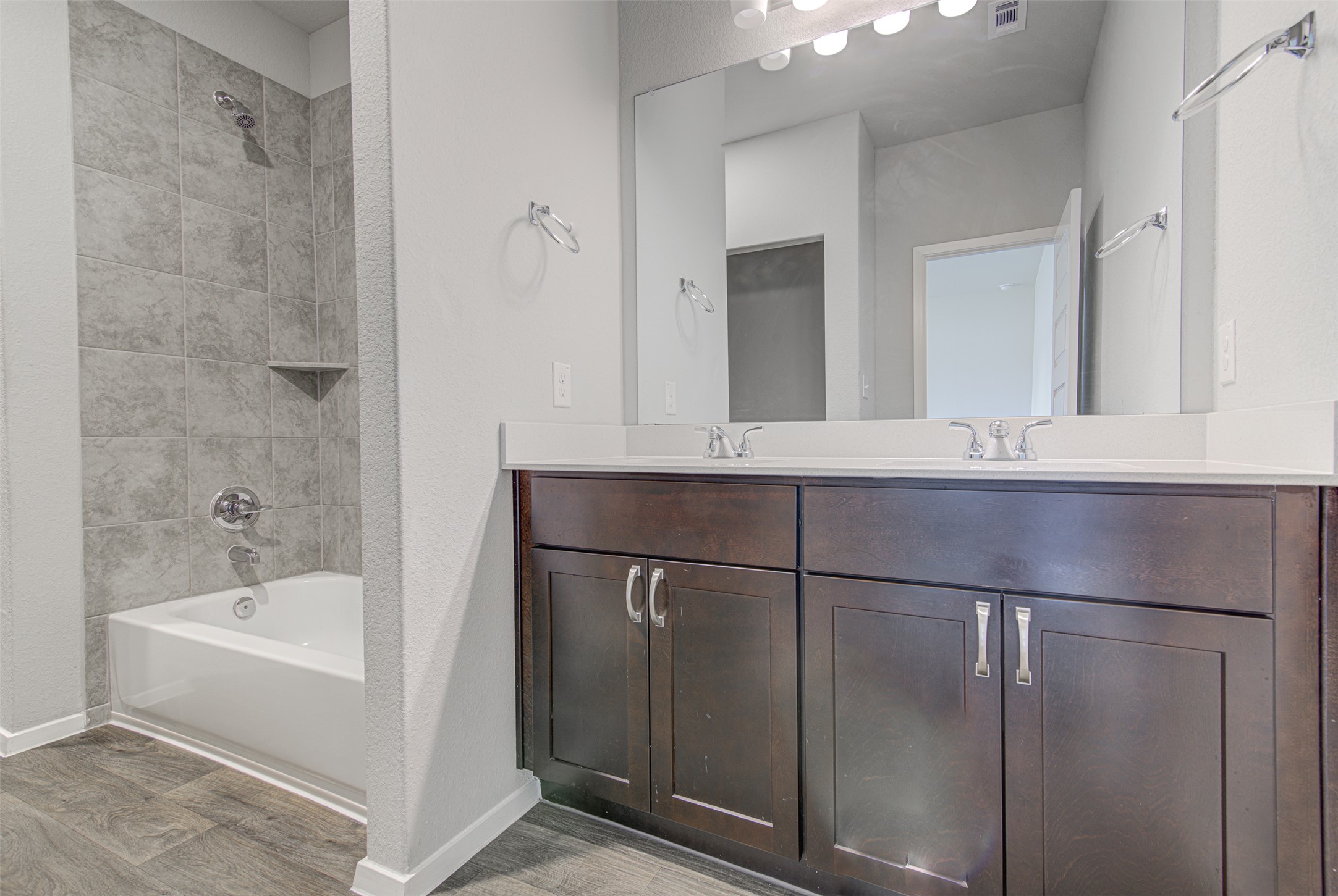 156 Tillage Road Elgin, TX 78621 - Photo 14 of 25 Modern bath offering dual vanities and a tiled shower-tub combination.