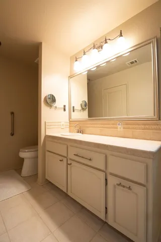 a bathroom with a granite countertop sink mirror and toilet