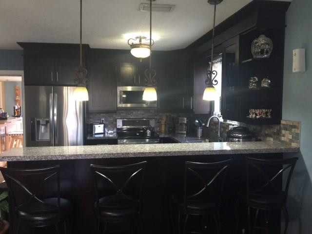 35 Tortuga Road Palm Springs, FL 33461 - Photo 1 of 17 a kitchen with stainless steel appliances kitchen island granite countertop a table chairs in it and wooden floors