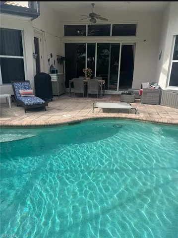 a living room with patio furniture and floor to ceiling window