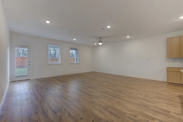 a view of an empty room with wooden floor and a window