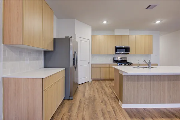 a kitchen with kitchen island a sink a stove a refrigerator and white cabinets
