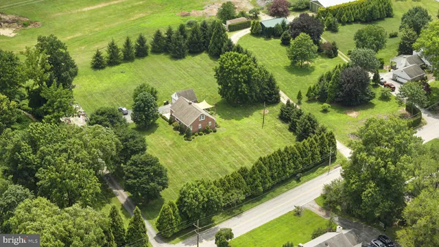 an aerial view of a residential houses with outdoor space and trees all around