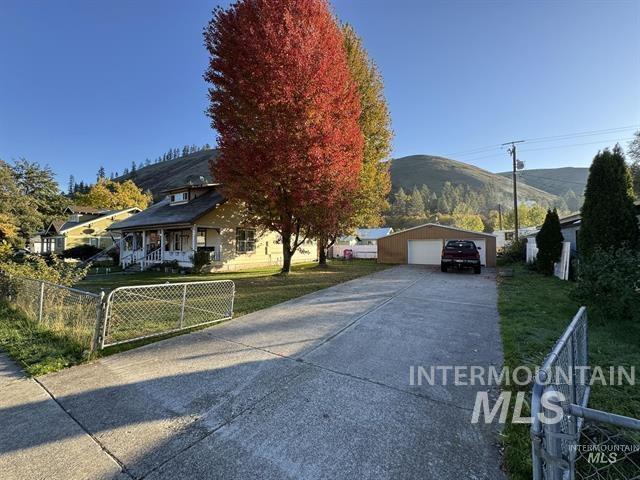 217 Main Street Kooskia, ID 83539 - Photo 2 of 34 View of front of home with a detached garage, an outdoor structure, a mountain view, covered porch, and a gate