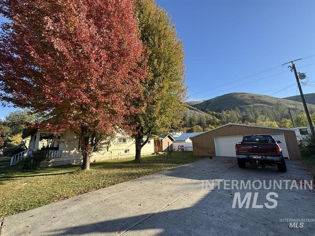 217 Main Street Kooskia, ID 83539 - Photo 28 of 34 View of front of house with a mountain view, an outdoor structure, a detached garage, and a front lawn