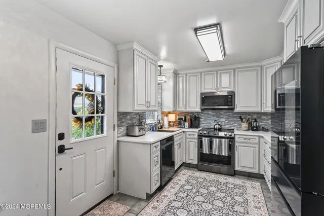 a kitchen with stainless steel appliances granite countertop a sink stove refrigerator and cabinets