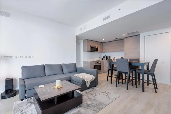 a living room with furniture and a dining table with kitchen view
