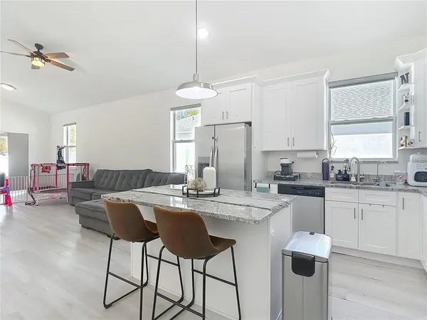 a kitchen with stainless steel appliances kitchen island granite countertop a dining table chairs and white cabinets