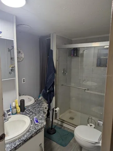 a bathroom with a granite countertop sink toilet a mirror and shower